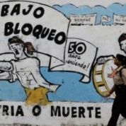 A pedestrian walks past graffiti in Cuba that reads 